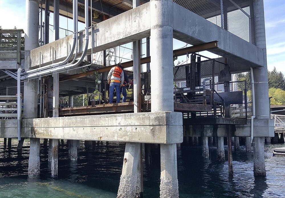 Public and Municipal Waterfront Infrastructure Worker performing maintenance on a public municipal waterfront structure supported by concrete piers over water